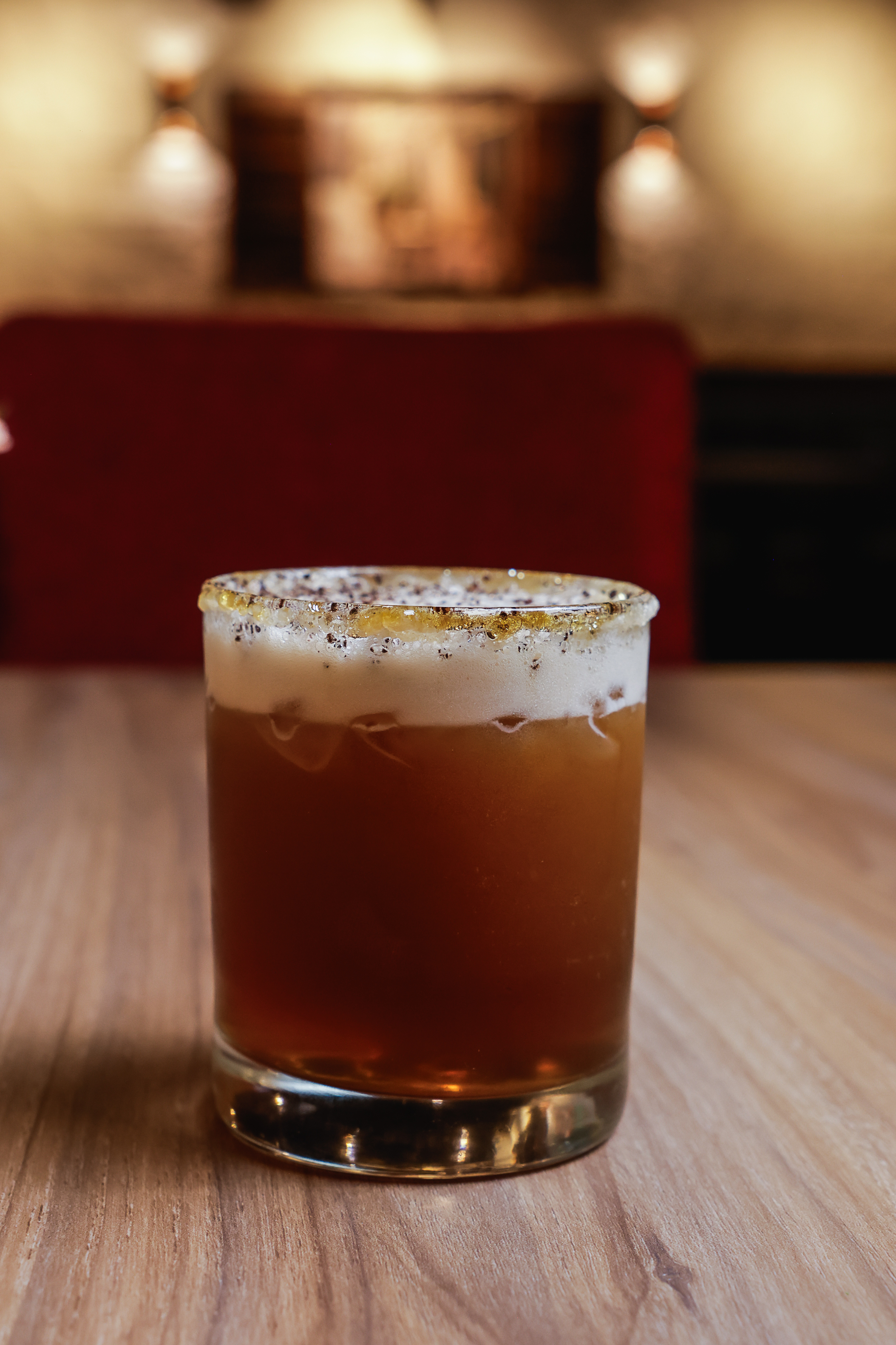 Carajillo servido en vaso old fashioned con escarcha dorada sobre mesa de madera en Luigi's