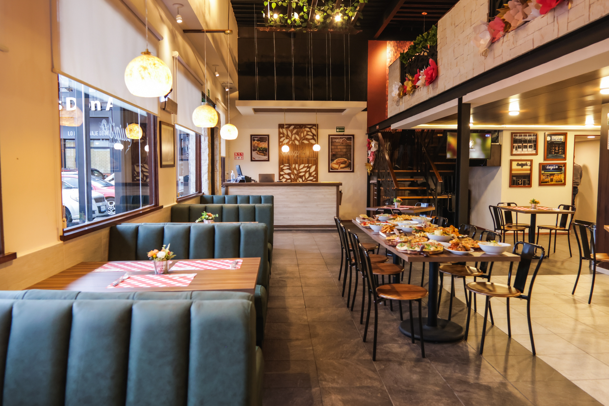 Interior de Luigi's Ristorante Italiano sucursal Tecnológico: bancas verdes acolchadas, mesas de madera con mantel cuadrillé rojo y barra de bienvenida